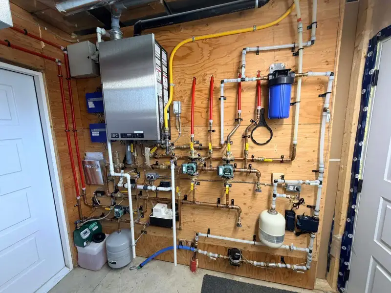 Barndominium mechanical room with boiler, zone pumps, radiant manifold, and water filtration
